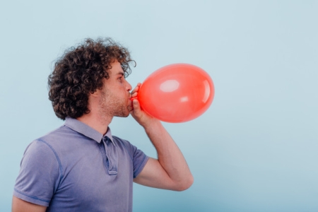jeune-homme-gonfle-ballon-rouge_184353-6