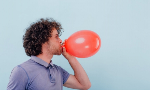 jeune-homme-gonfle-ballon-rouge_184353-6